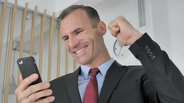 Man Celebrating Success While Using Smartphone