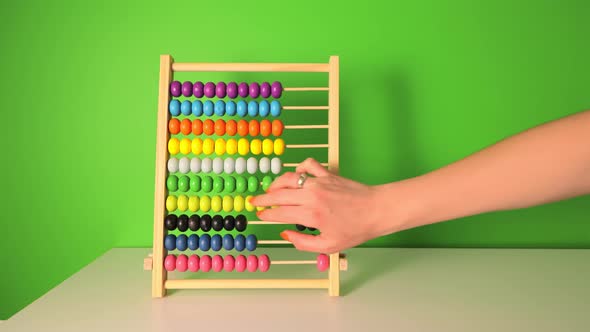 Female Hand Slowly Counts on a Children's Wooden Abacus