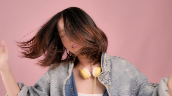 Happy pretty Asian teenager girl dancing and flicking hair on pink background, Slow motion shot.