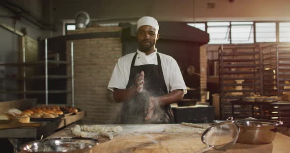 Animation of happy african american male baker cleaning hands from four and smiling at camera