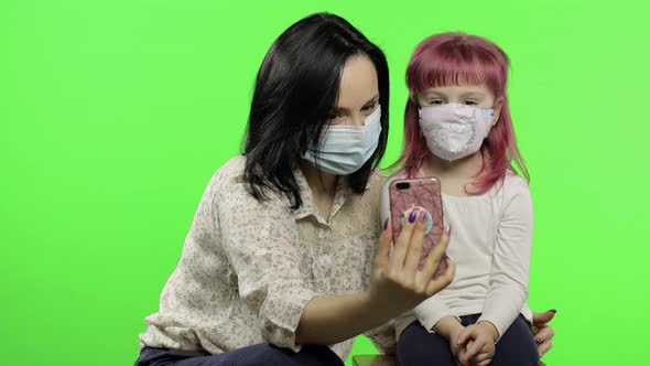 Mother, Daughter Wearing Medical Mask Holding Smart Phone Talking on Video Call