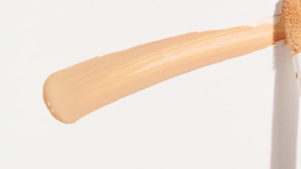 Macro Shot and Slow Motion of a Brush Applicator Smear Concealer Isolated on White Background