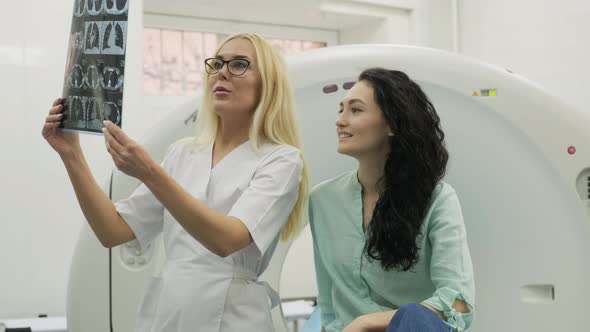 Woman doctor radiologist explains good results of CT scanning for young female