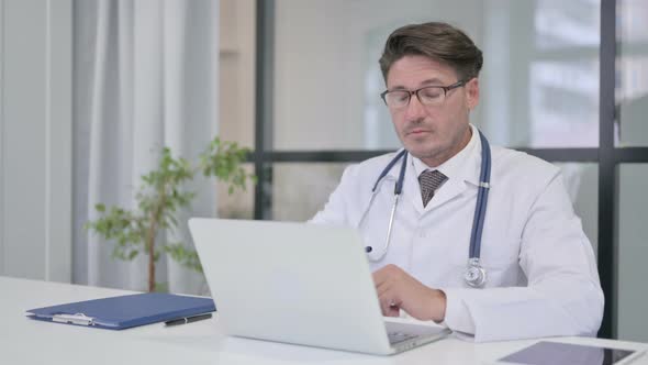 Doctor with Laptop Looking at the Camera in Clinic
