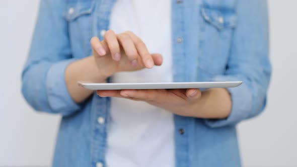 Close Up on the Hand of Young Handsome Woman Pointing and Touching the Screen of a Tablet with Her