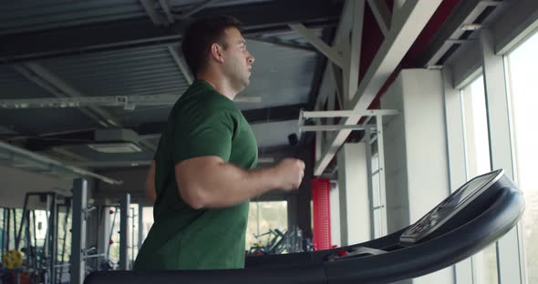 Caucasian Man Training at Gym, Running on Treadmill, Side View