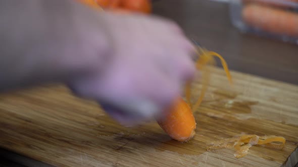 Closeup peeling fresh ripe carrot - Hand in front of carrot with carrot in focus 24fps