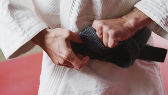 Judoka tightening the black belt