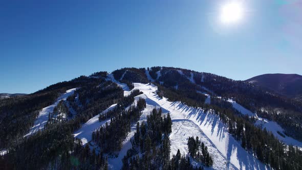 Drone shot over looking a ski mountain with the sun in frame