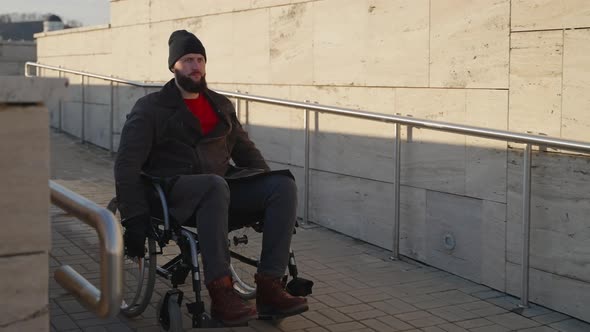 Adult Handicapped Man in Manual Wheelchair is Moving on Ramp in Modern City