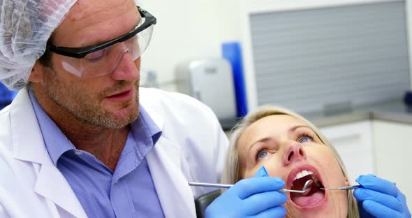 Dentist examining a female patient with dental tools