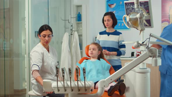 Stomatologist Doctor Explaining To Mother the Dental Process of Intervention