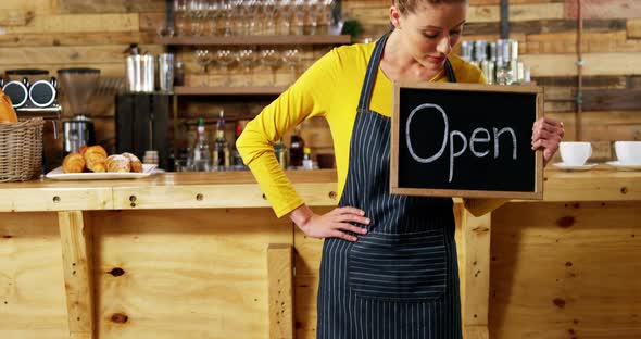 Waitress showing slate with open sign in cafe