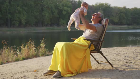 Grandfather Holding Newborn Baby Granddaughter Outdoors