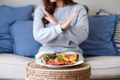A woman making crossed arms hand sign to refuse food on the table for dieting - PhotoDune Item for Sale