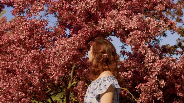 Cute Redhead Woman Stands Near Apple Tree Blossom and Walks Away