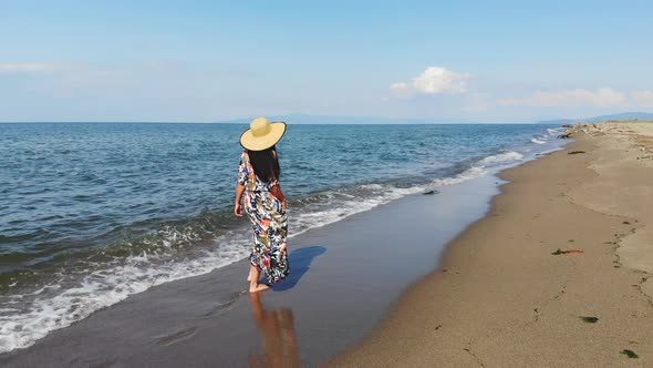 Brunette Girl in Hat Walking at Seaside