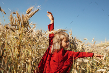 Little Happy Girl in Red Dress on a Sunny Field of Rye