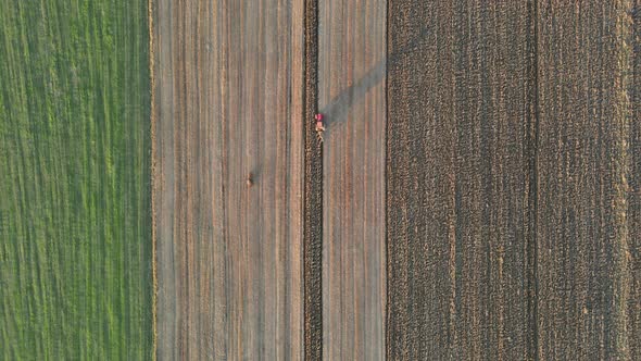 Aerial View of Agricultural Field Farmer in Tractor at Work Preparing Plowing Land