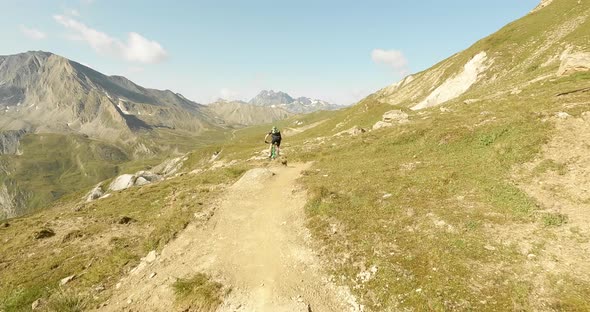 Mountainbiker on a nature single trail with huge mountains and cliffs in the background. Downhill bi