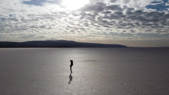 Young woman practicing yoga in the middle of a salt flat. Balancing yoga asana Dancer Pose (Nataraja