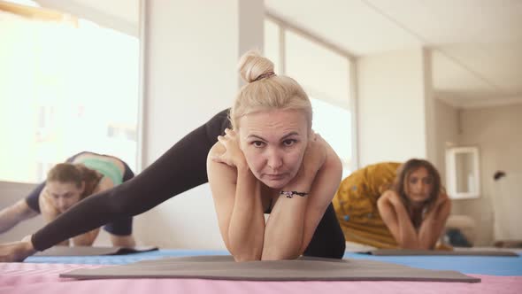 Yoga Class in the Studio Three Women Rest Their Elbows on the Floor and Stretch Their Leg to the