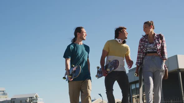 Happy caucasian woman and two male friends, walking, talking and spending time together on sunny day