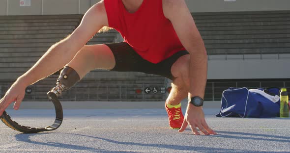 Low section of caucasian disabled male athlete with running blade stretching