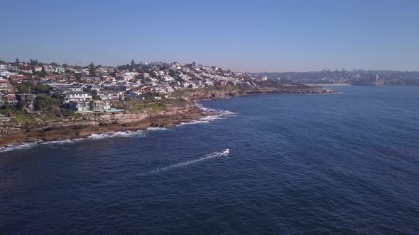 Boat passing the coastal waterfront houses with Pacific Ocean water view in Sydney - Aerial