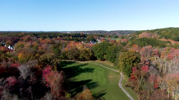 Majestic autumn colors with small town of Haverhill behind, drone descending view