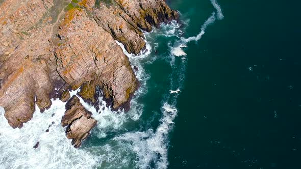 Rocky coastline cliff, with white water breaking onto shore, scenic vacation destination