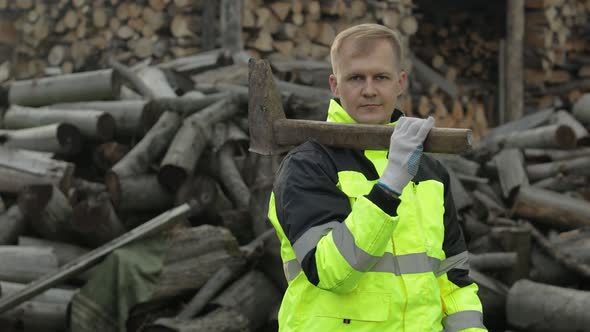Lumberjack in Reflective Jacket. Man Woodcutter with Big Axe. Sawn Logs, Firewood Background