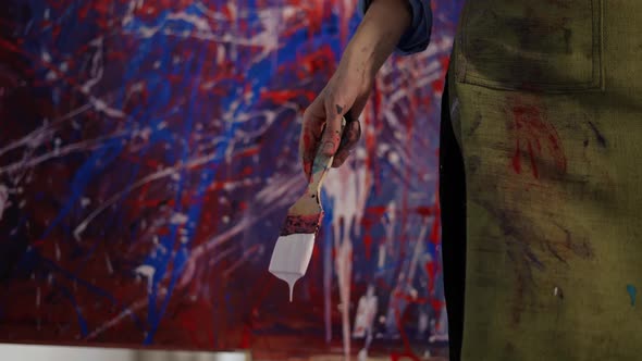 Woman Holding Brush Full of White Paint Then Splashing It on Canvas