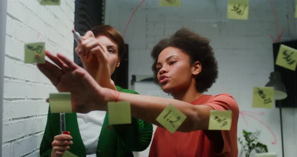 A Woman is Drawing a Business Strategy on a Glass Board Working with Assistant