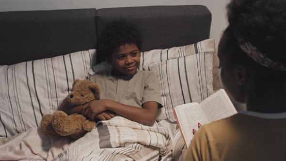 Woman Reading Book to Son at Night