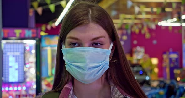 Portrait of a Caucasian Woman with a Bionic Hand Wearing a Protective Mask Who Removes the Medical