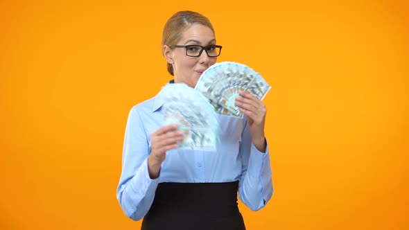 Smiling Business Lady Showing Dollar Bills on Orange Background, Investment