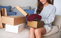 A woman receiving and opening a postal parcel box of clothing at home for delivery - PhotoDune Item for Sale