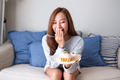 A happy young woman holding and eating a piece of lemon pound cake at home - PhotoDune Item for Sale