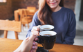 A young woman and a man clinking coffee mugs together in cafe - PhotoDune Item for Sale