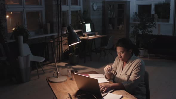 Woman Working Alone In Dark Empty Office