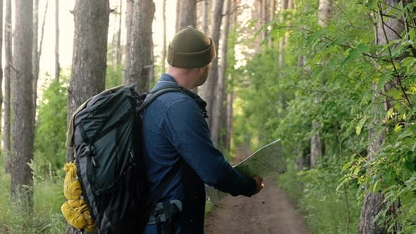 Man with a backpack is traveling on foot along forest paths