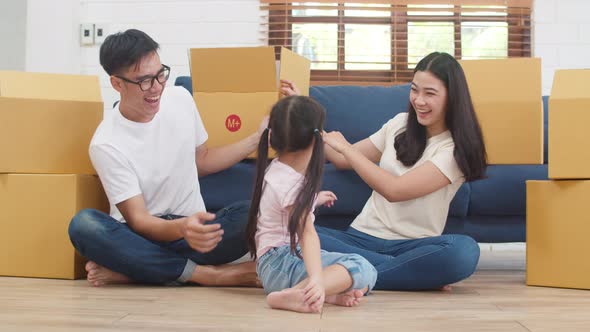 Mom, Dad, and daughter playing together during unpacking in new home after moving in relocation.