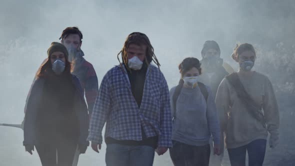 Group of Young People in Gas Mask Going Through the Toxic Smoke in a Desolate and Burned Landscape.