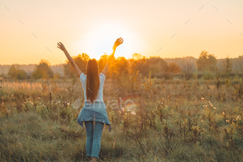 irl Outdoors raising hands in sunlight rays. Beautiful Teenage Model girl in white dress running on the Field, Sun Light. Glow Sun. Free Happy Woman