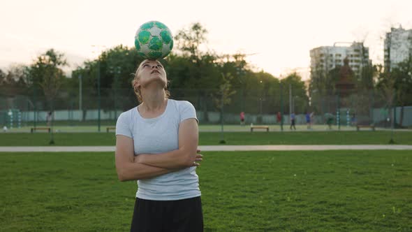 Woman Football Soccer Player Practicing Tricks with Ball on Head in the Park at Sunset