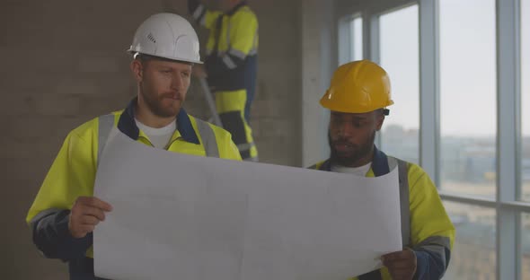 Diverse Builders Looking at Blueprint and Planning Room Renovation