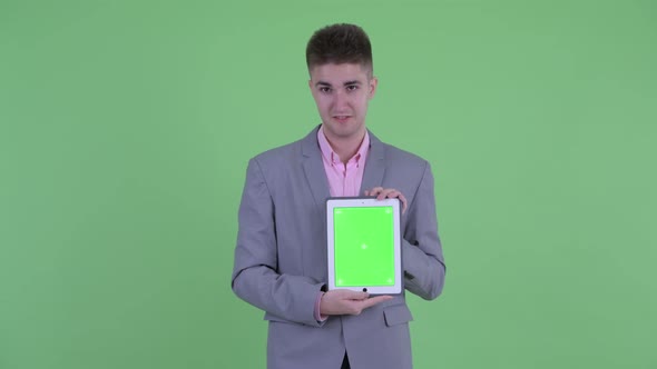 Happy Young Businessman Talking While Showing Digital Tablet