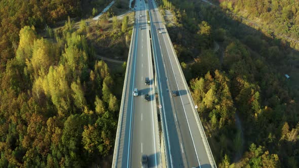 Highway traffic going into a tunnel on scenic road, aerial pan up