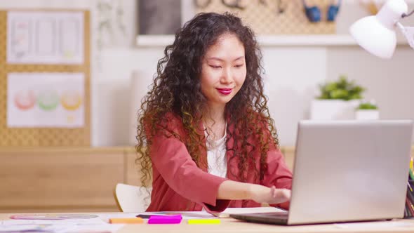 concentrated young Asian businesswoman working on computer at office or home, communicating with cli